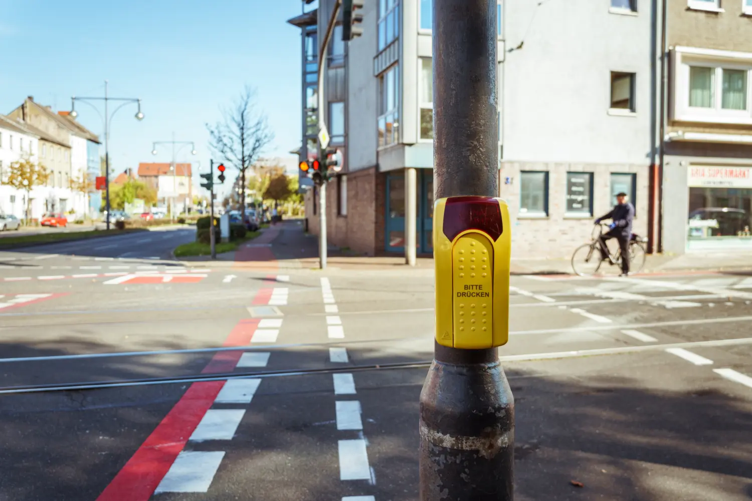 Logos Ingenieurplanungs GmbH – Dieses Bild zeigt einen gelben Fußgängerampelknopf an einem Pfosten an einem städtischen Zebrastreifen.